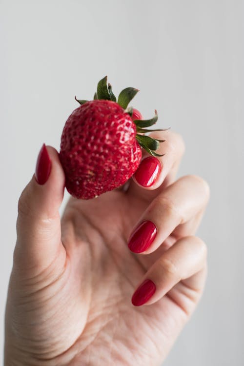 Close-Up Shot of a Person Holding a Strawberry