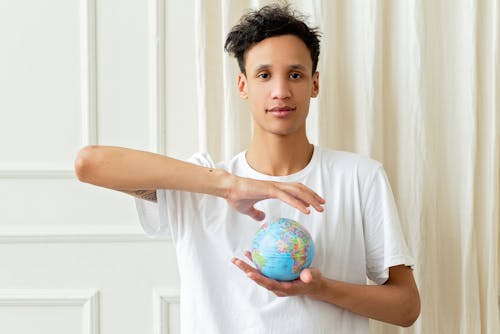A Man in White Shirt Holding a Globe