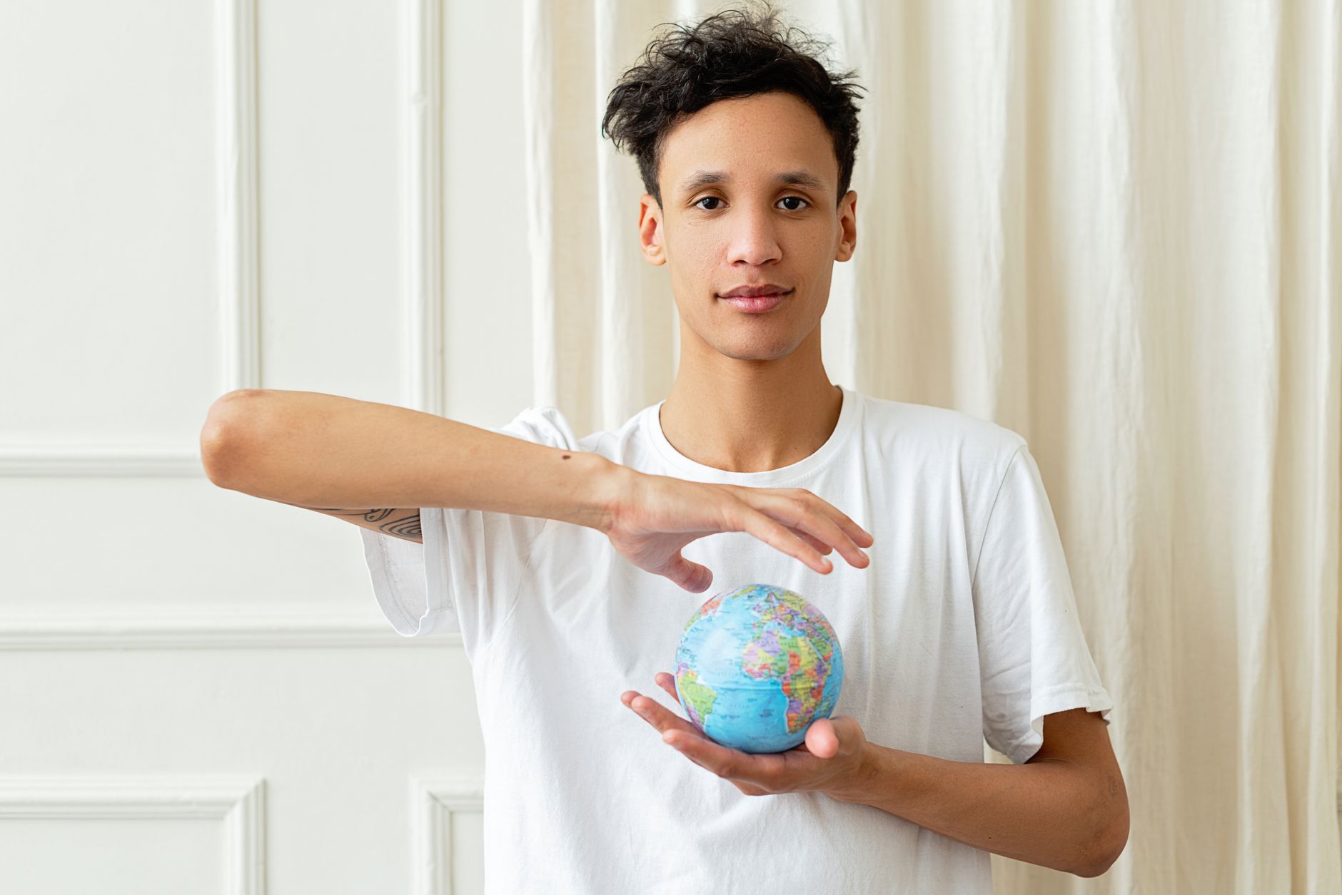 Portrait of a young man holding a globe, symbolizing global awareness and volunteerism.