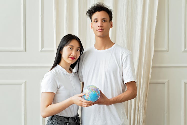 A Man And Woman Holding A Globe 