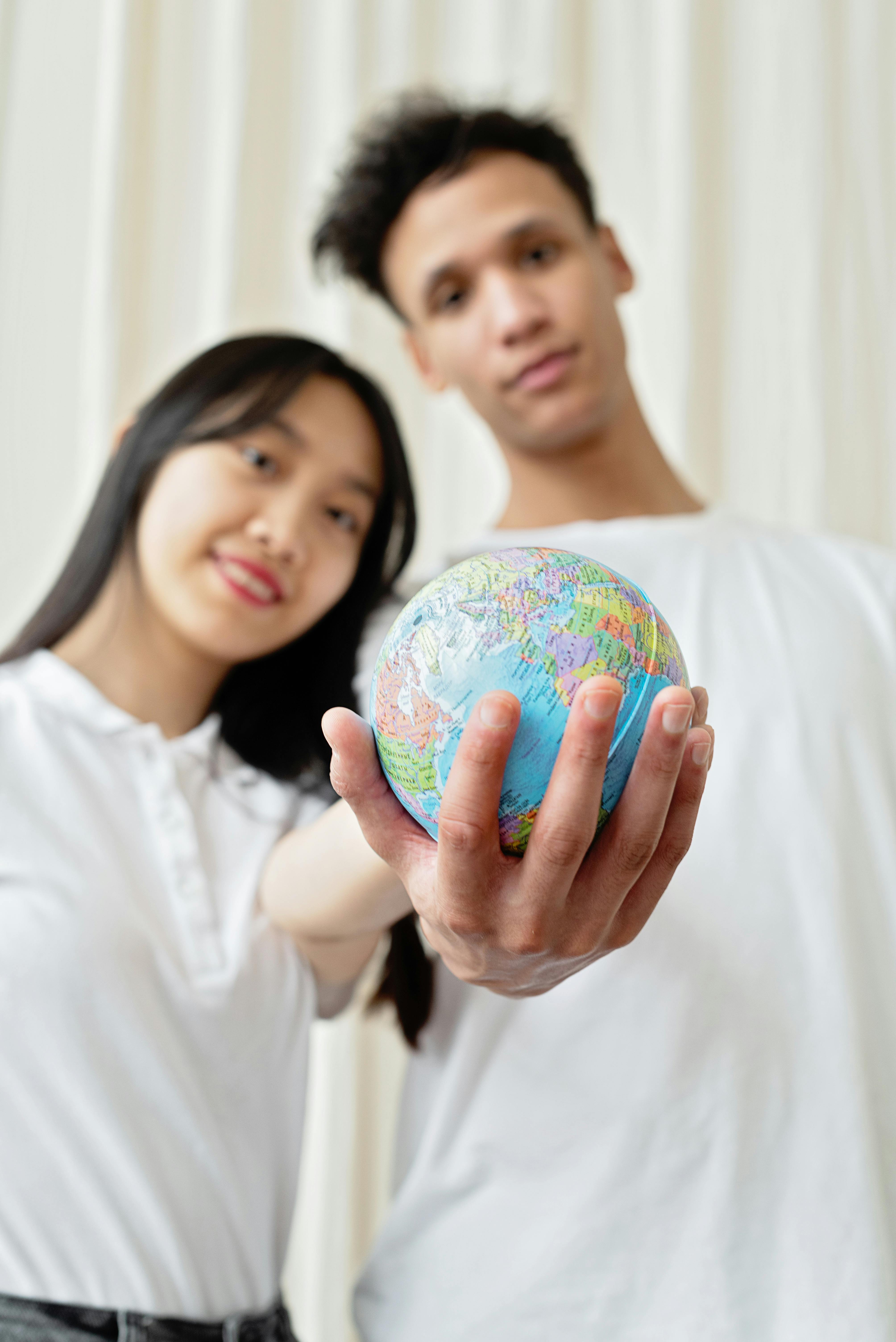 Young adults holding a small globe, symbolizing unity and environmental awareness.