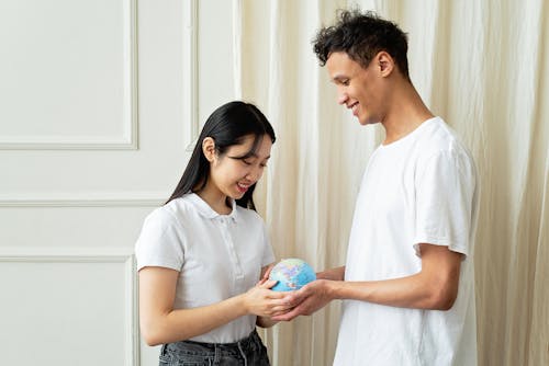 Man and Woman in White Shirts Holding a Globe
