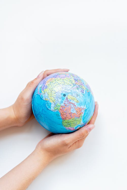 Person Holding a Globe on White Surface