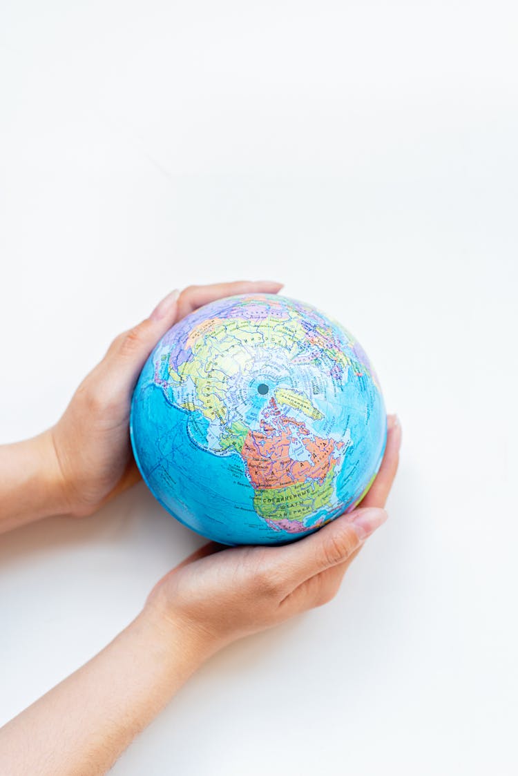 Person Holding A Globe On White Surface