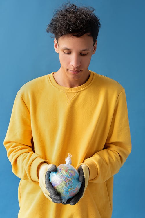 A Man wearing Gloves holding a Globe