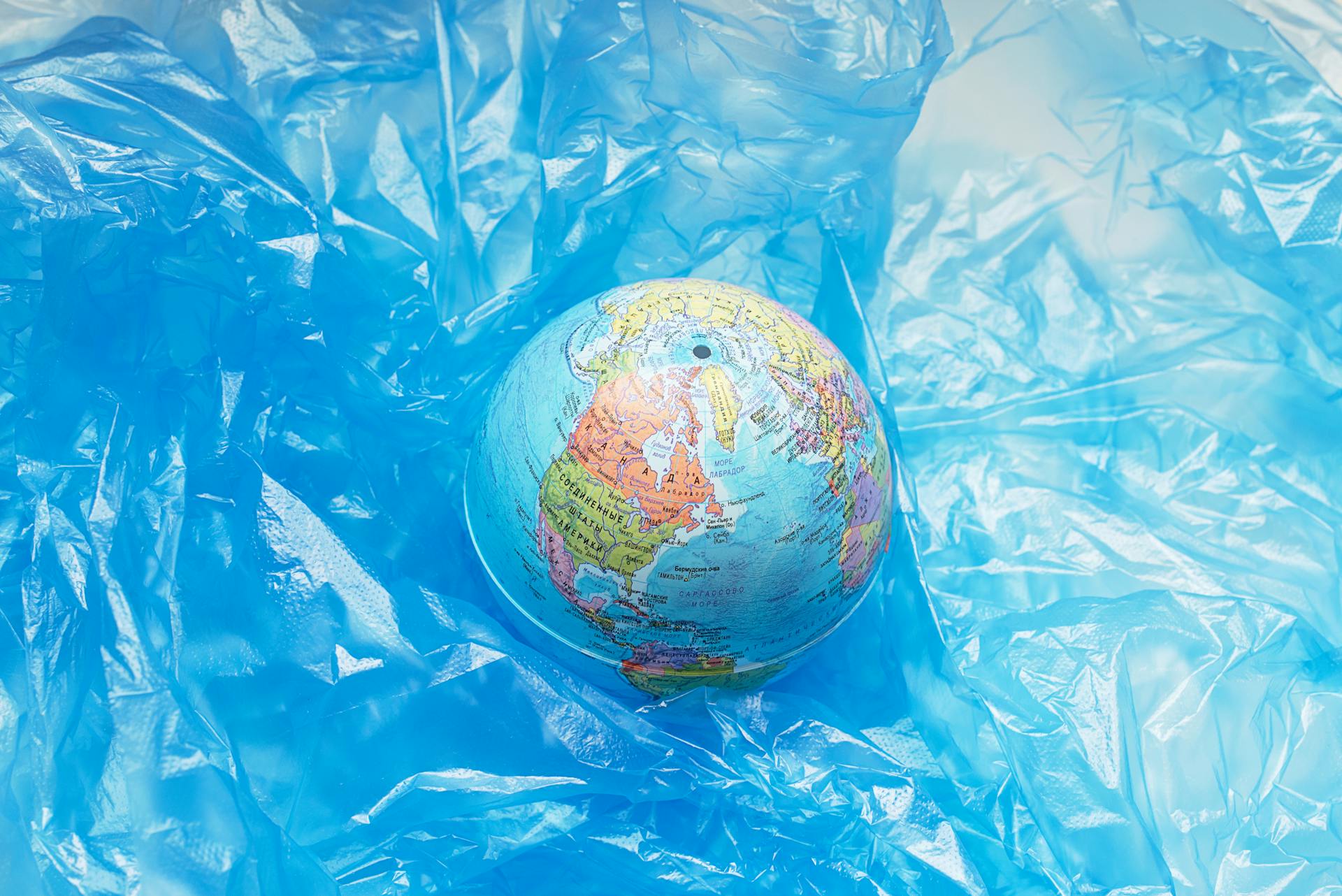 A globe wrapped in blue plastic, symbolizing global pollution and environmental issues.