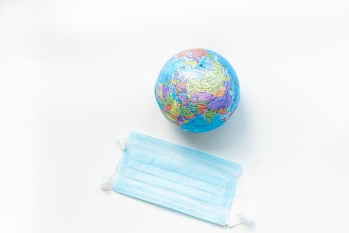 A Blue Surgical Mask Beside a Globe 