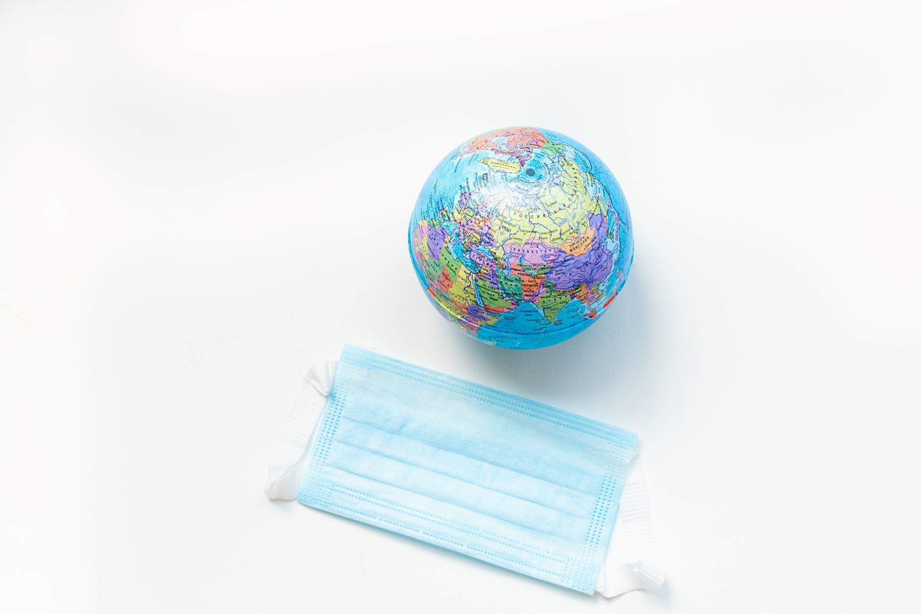 A globe and a face mask symbolizing global health awareness on a white background.