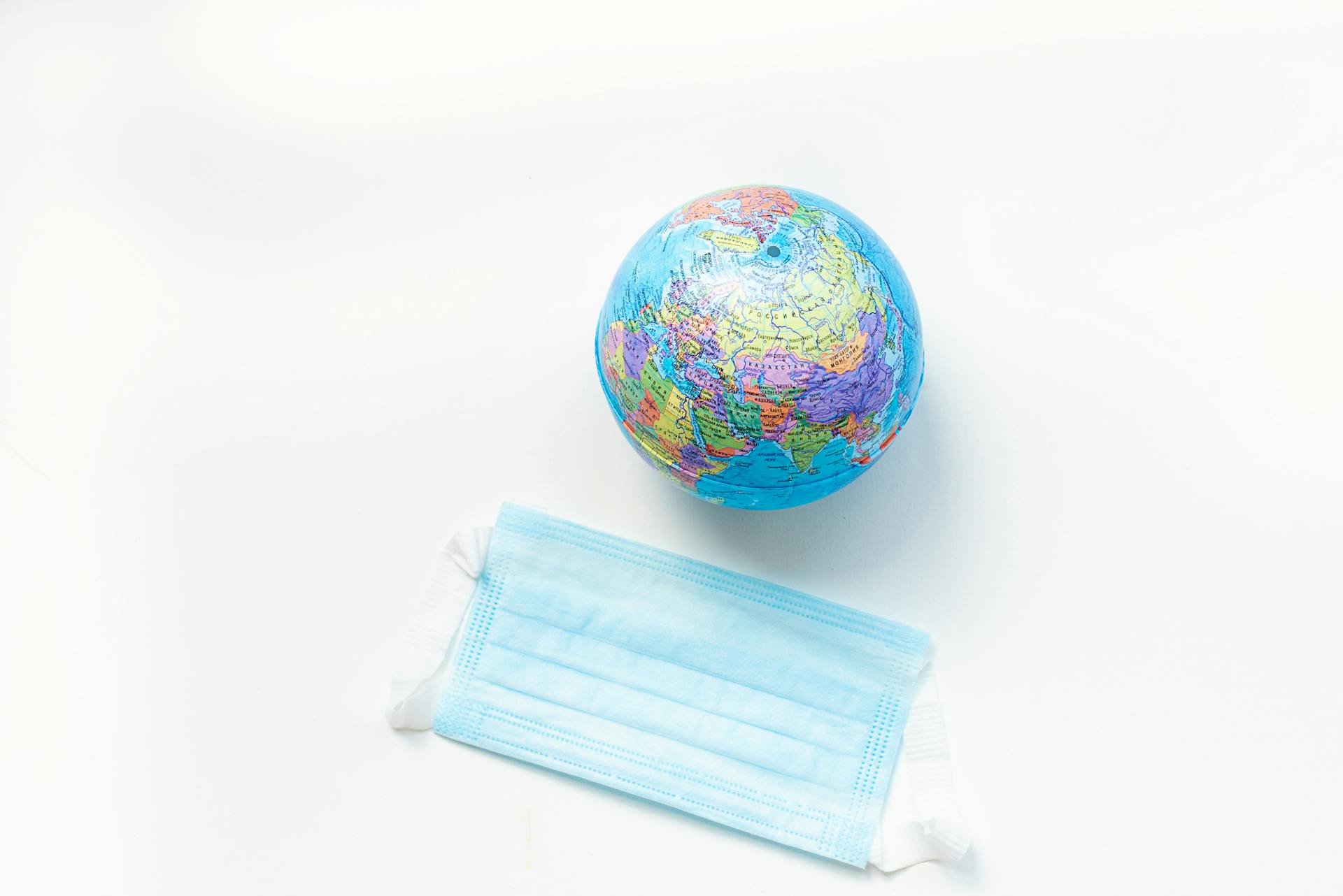 A globe and a face mask symbolizing global health awareness on a white background.