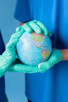 Two people in blue scrubs and gloves holding a globe, symbolizing global health care and environmental protection. 8542561