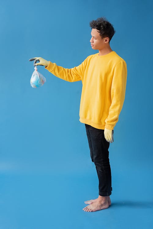 Man in Yellow Sweater holding a Plastic with Globe 
