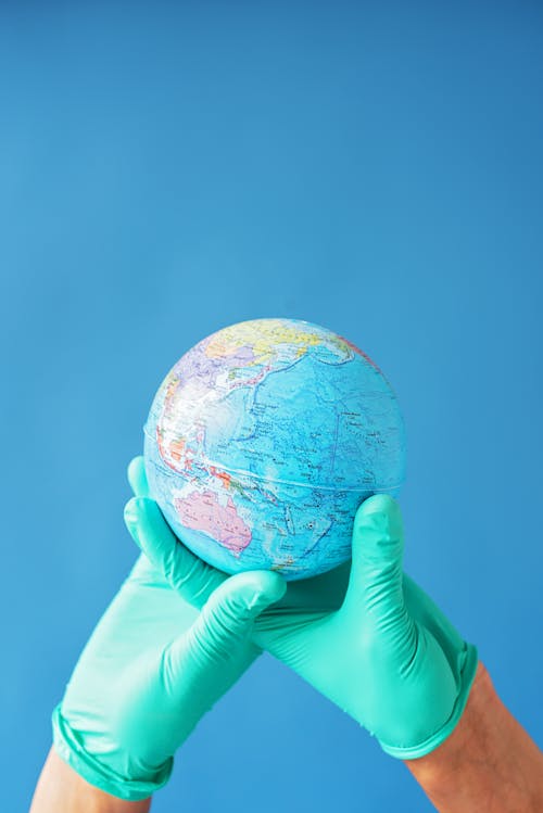 Free Person Holding a Globe in Blue Background Stock Photo