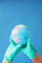 Person Holding Blue and Brown Globe