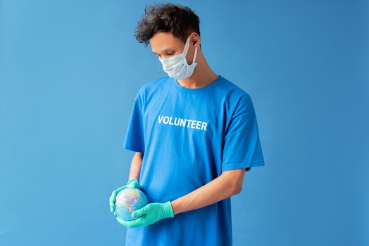 Man in mask holding a globe, symbolizing global environmental care and volunteerism.