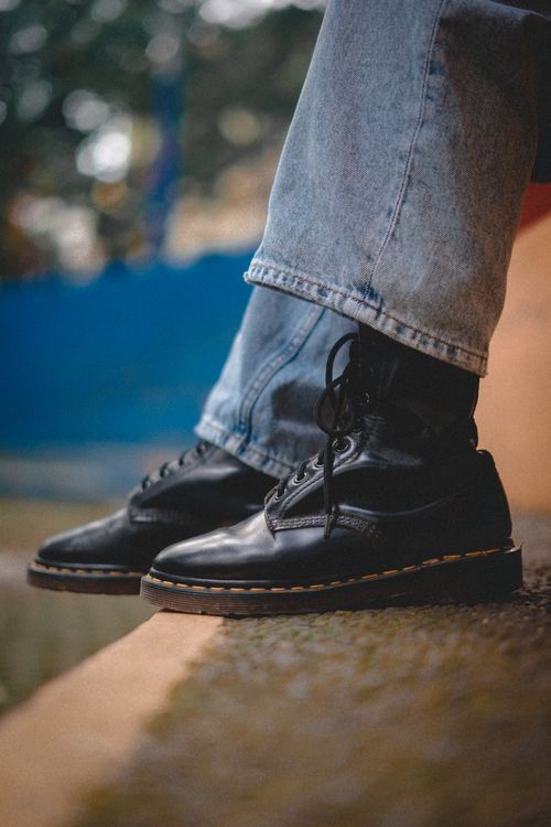 Free Close-up of black leather boots paired with denim jeans, outdoors in a stylish setting. Stock Photo