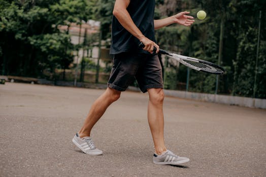 Close-up of a tennis player practicing on an outdoor court, ready to serve.