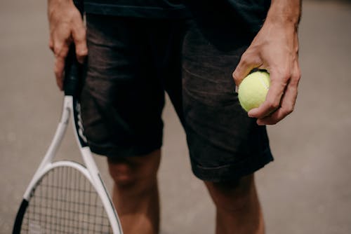Man Holding a Tennis Ball and Racket