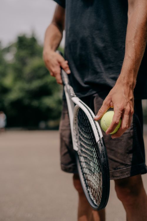 Free Adult male tennis player holding a racket and ball outdoors. Stock Photo