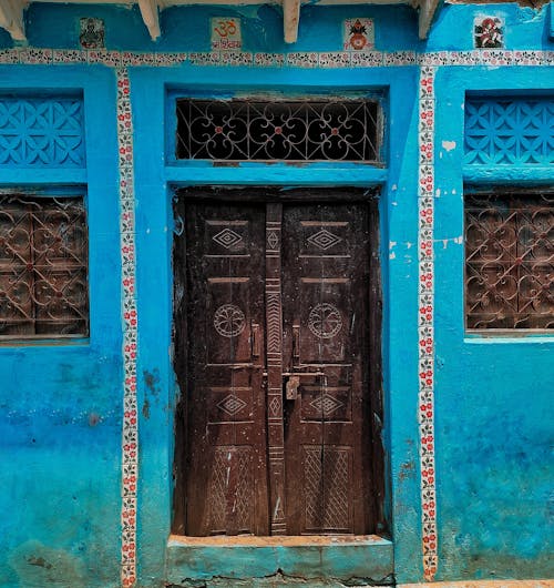 A Wooden Door Between Blue Concrete Wall