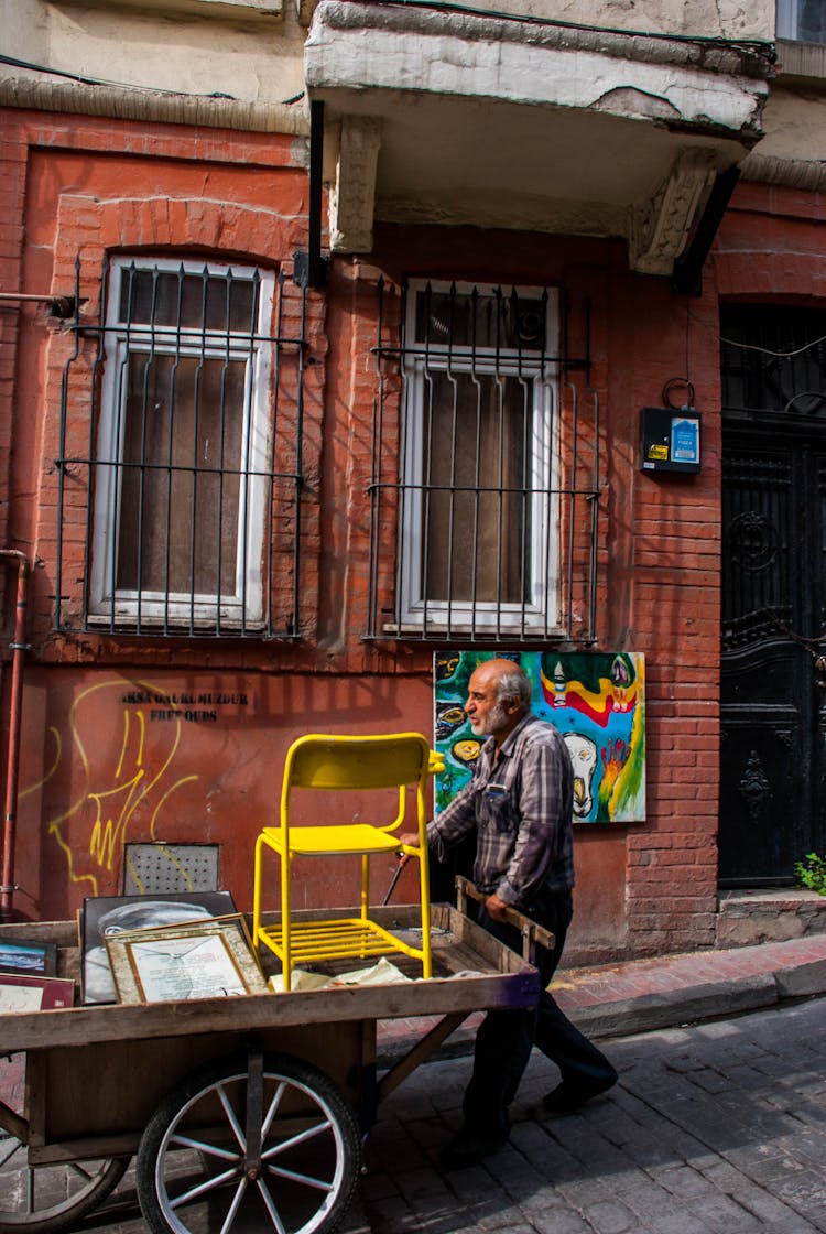 Elderly Man Pushing A Wooden Cart