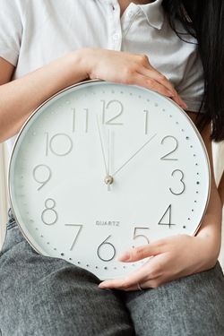 Person holding a large round clock — photo by Mikhail Nilov on Pexels