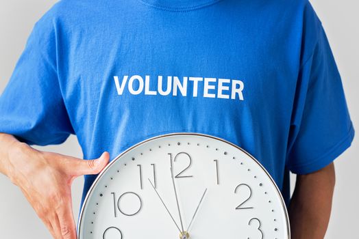 Close-up of a volunteer holding a wall clock, symbolizing time commitment.