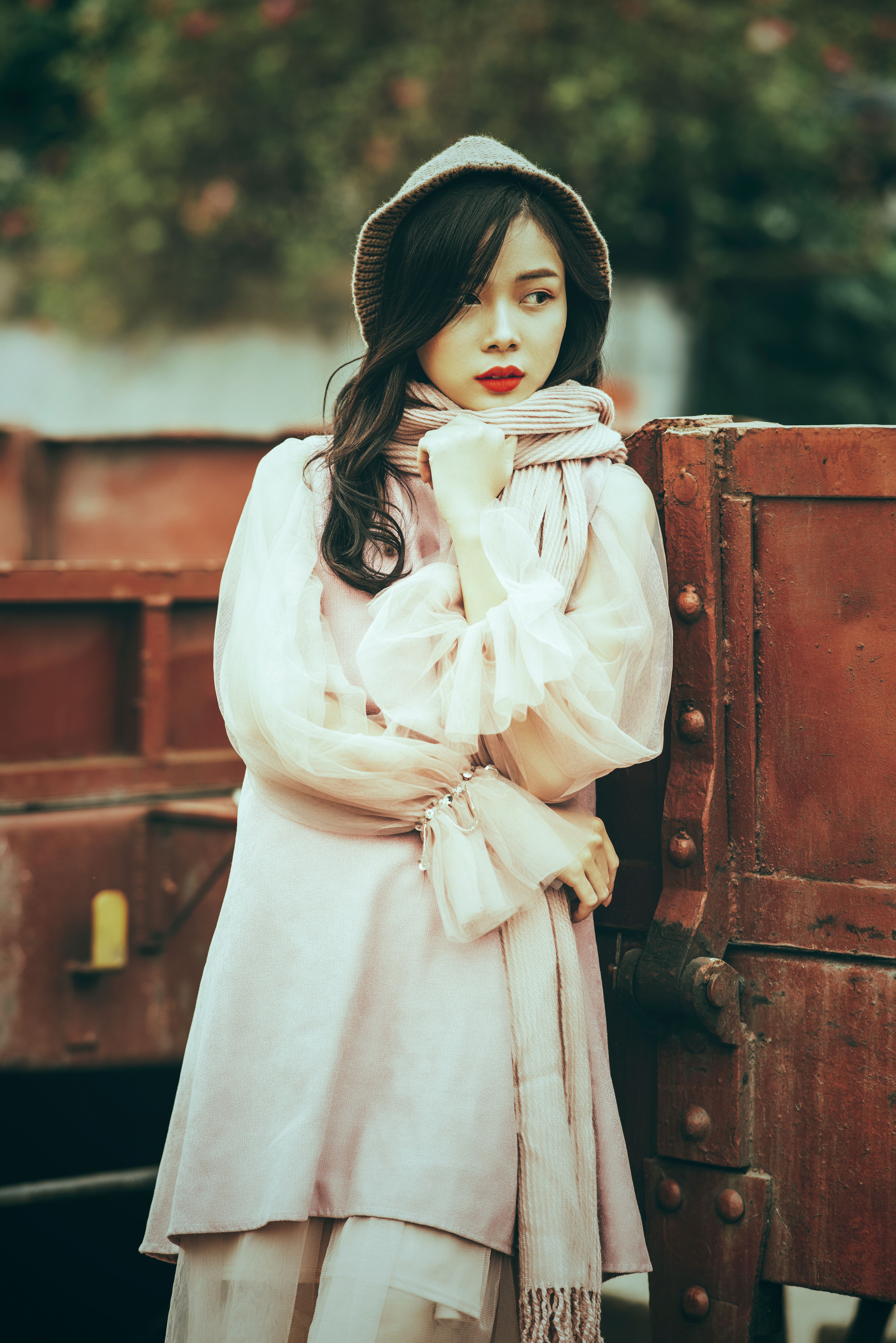A fashionable woman in a white dress and bucket hat posing outdoors, exuding style and elegance.