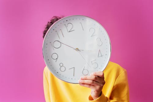 Free Person Holding An Analog Wall Clock With Purple Background Stock Photo