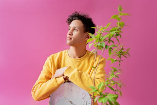 Man leaning on a Clock while looking away 