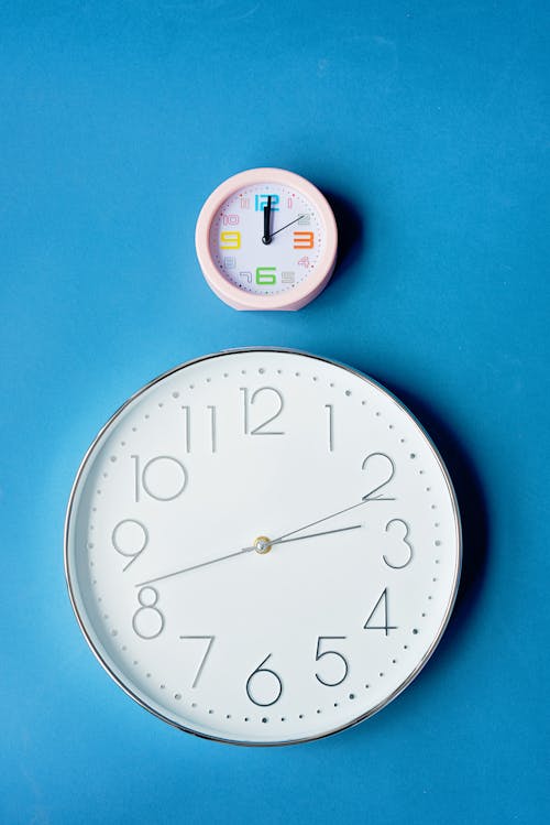 Free Alarm Clock and a Wall Clock on Blue Surface Stock Photo