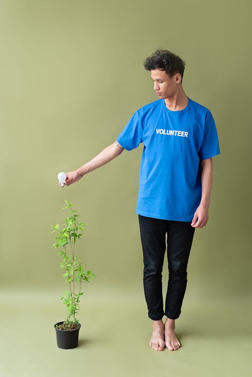 A Man Standing Holding a Light Bulb Above a Potted Plant