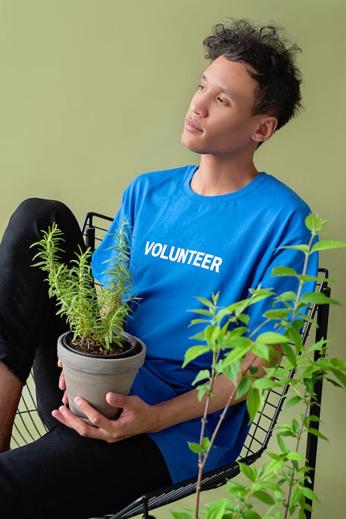Free A Man Wearing a Blue Shirt Holding a Potted Plant Stock Photo
