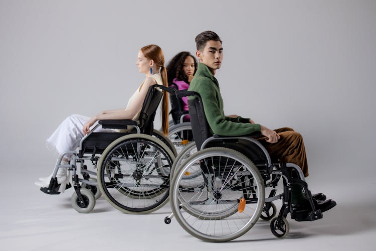 Three People Sitting On Wheelchairs