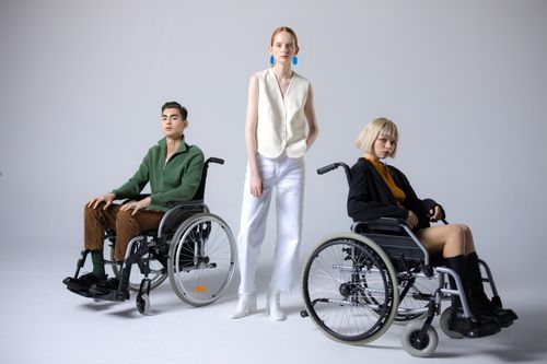 Free Diverse group showcasing inclusive fashion with wheelchairs in a studio setting. Stock Photo