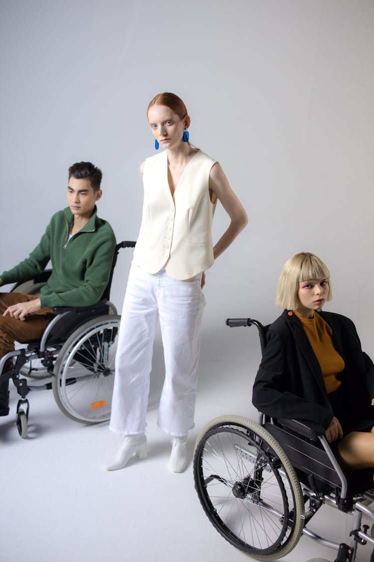 Woman Standing Between Two People In Wheelchairs