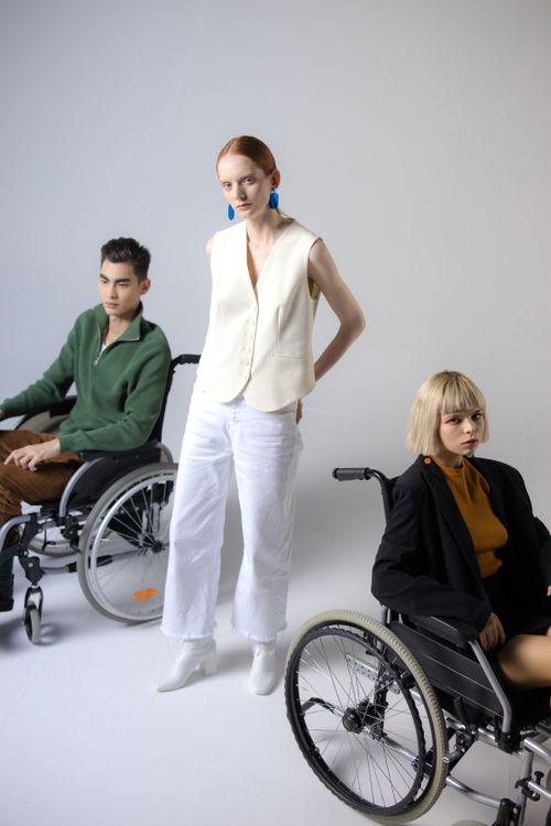 Free Three individuals in stylish attire, featuring two in wheelchairs, on a white backdrop. Stock Photo