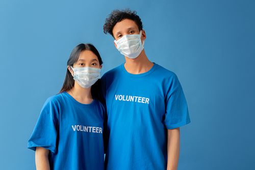 Free Asian volunteers in blue shirts and face masks symbolizing pandemic safety and community service. Stock Photo