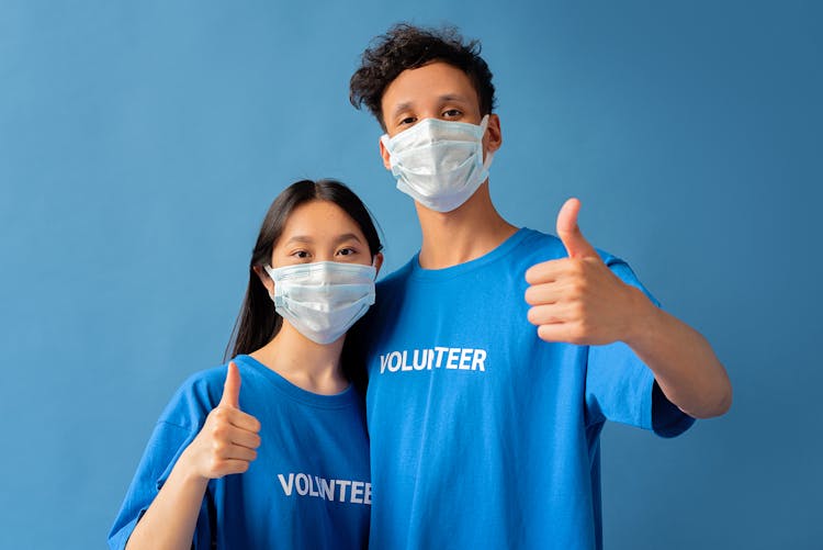 Volunteers In Face Masks And Matching Shirts Giving A Thumbs Up