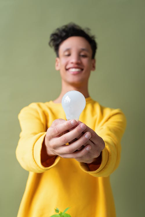 A Man in Yellow Sleeves Holding a Lightbulb