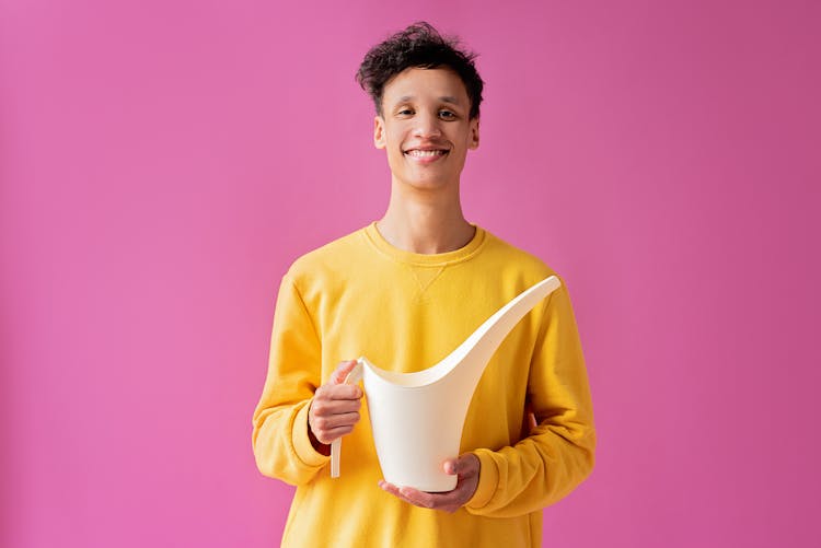 A Handsome Young Man Holding A Long Spout Plastic Watering Can