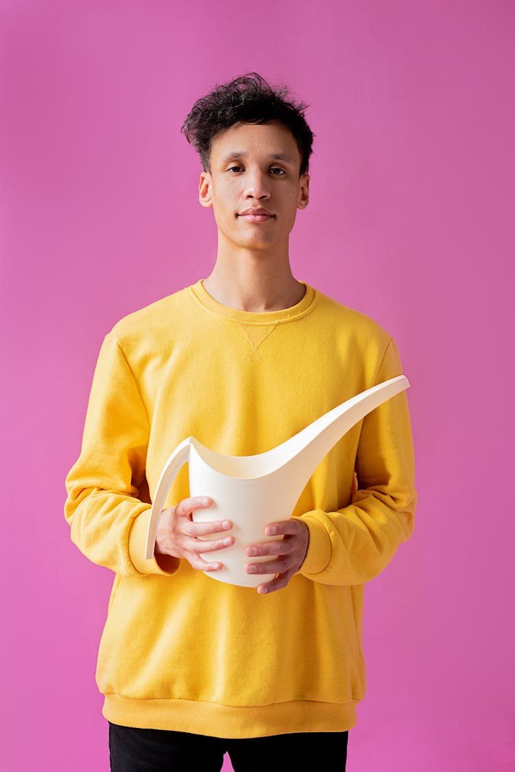 A Handsome Young Man Holding A Long Spout Plastic Watering Can