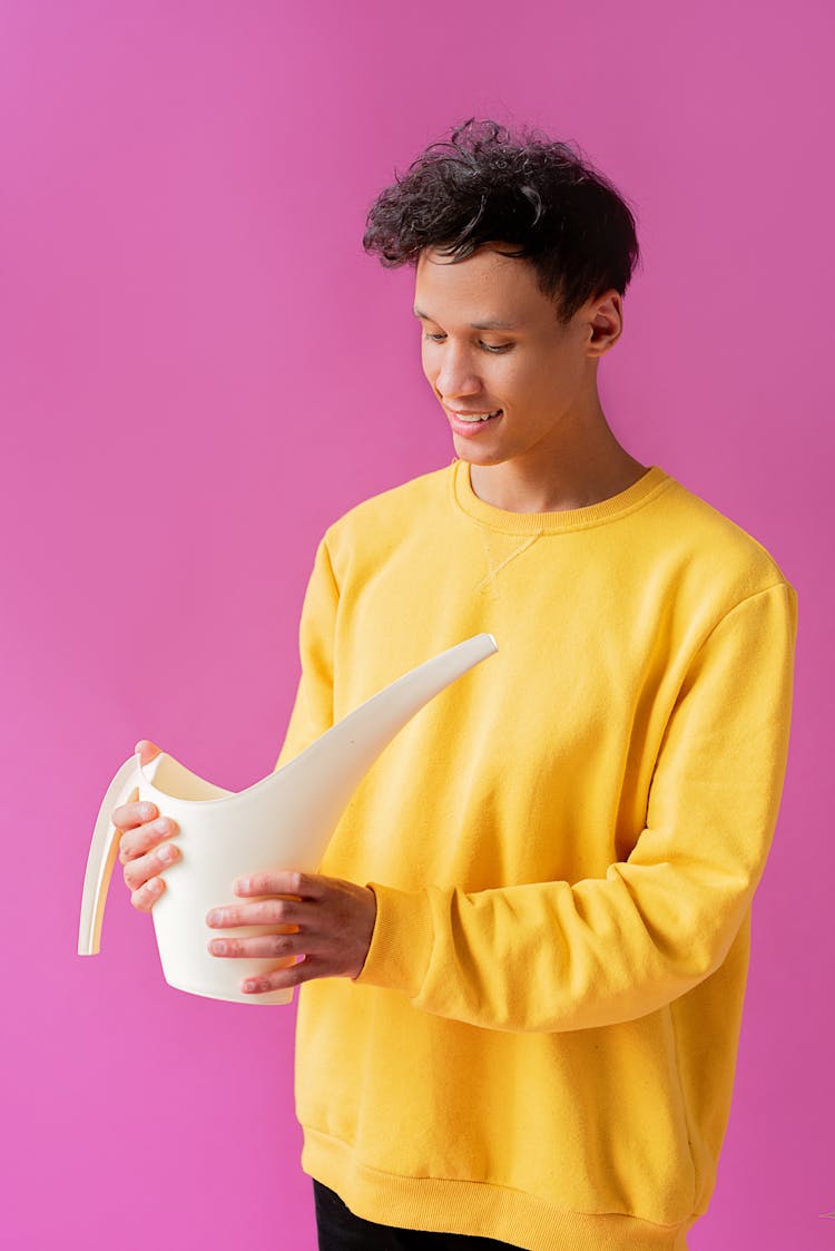 A Handsome Young Man Holding A Long Spout Plastic Watering Can