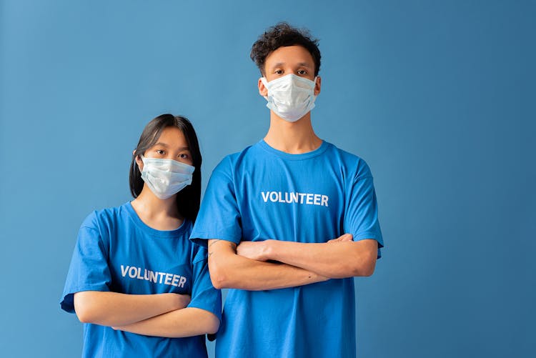 Man And Woman With Face Masks Standing With Arms Crossed