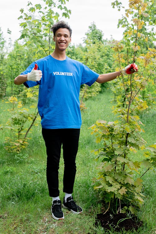 A Volunteer Man Wearing Gloves Holding a Plant