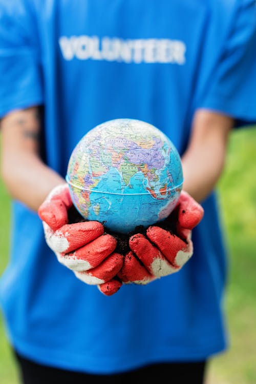 Man Holding Figurine of Planet Earth 