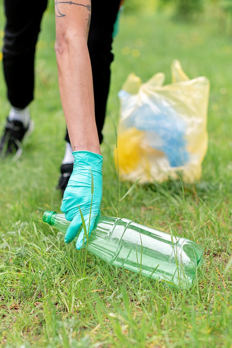 Person Wearing Latex Gloves Picking Up A Plastic Bottle