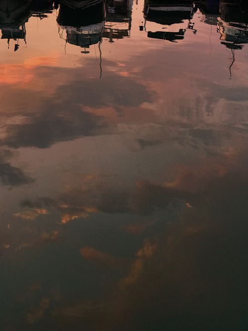 Free Atmospheric reflection of boats on a lake during sunset, capturing serene colors and calm waters. Stock Photo