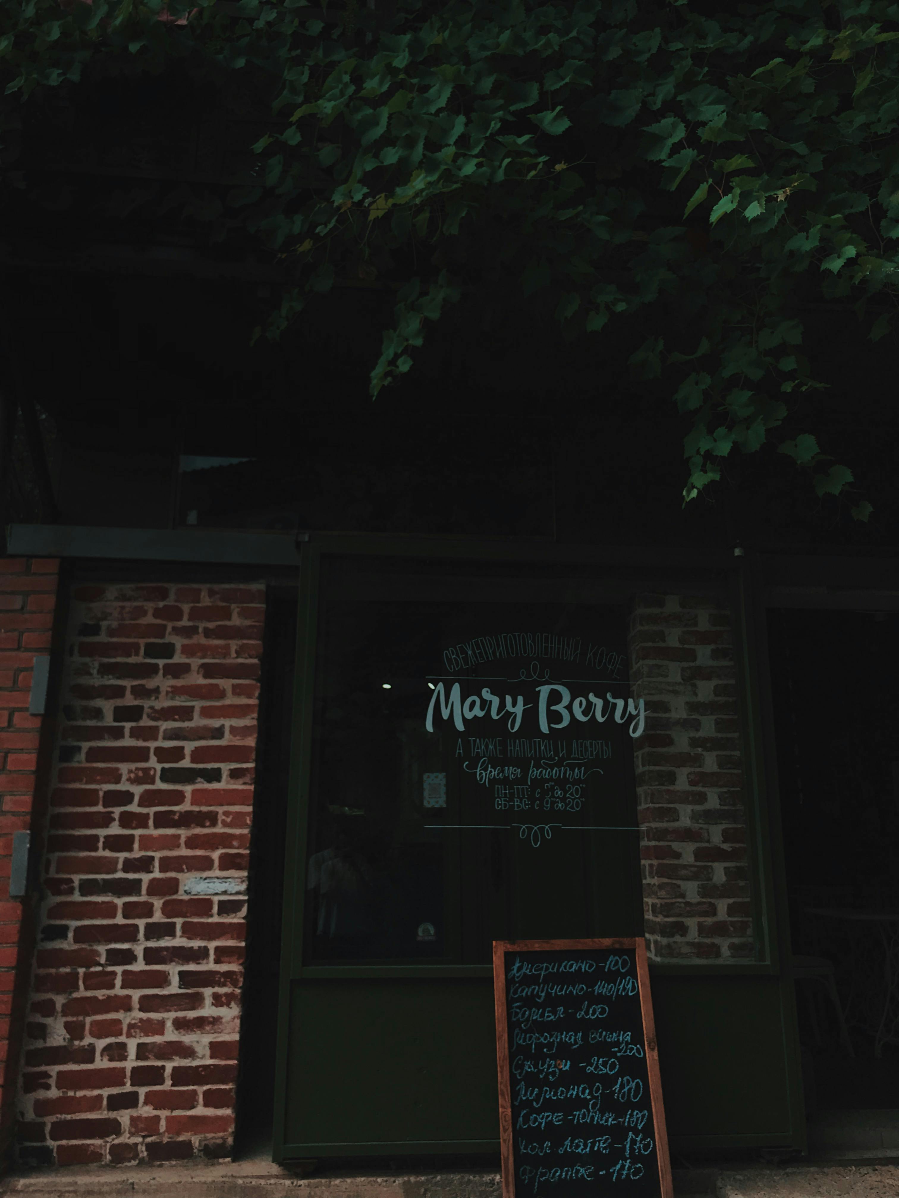Exterior of a cozy coffee shop with rustic brick and lush greenery.