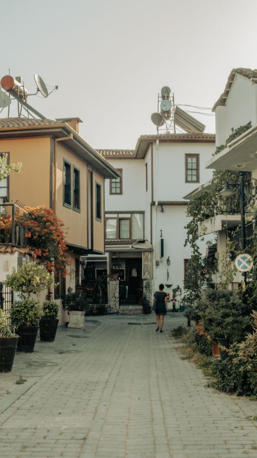Free A quaint street in a Mediterranean village with colorful houses and lush plants. Stock Photo