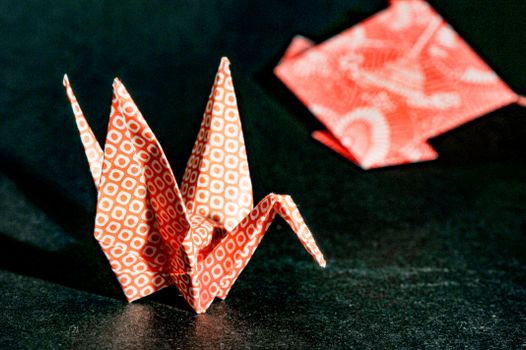 Close-up of a red origami crane with geometric patterns, highlighting delicate craftsmanship.